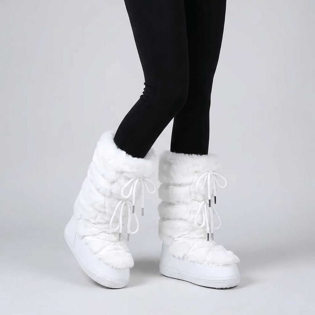 Pair of women's fur lined snow boots set on the snow